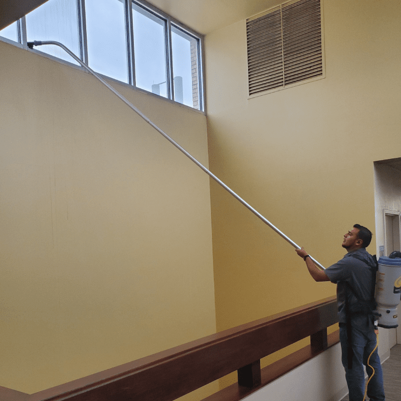 a man cleaning a window with a long pole